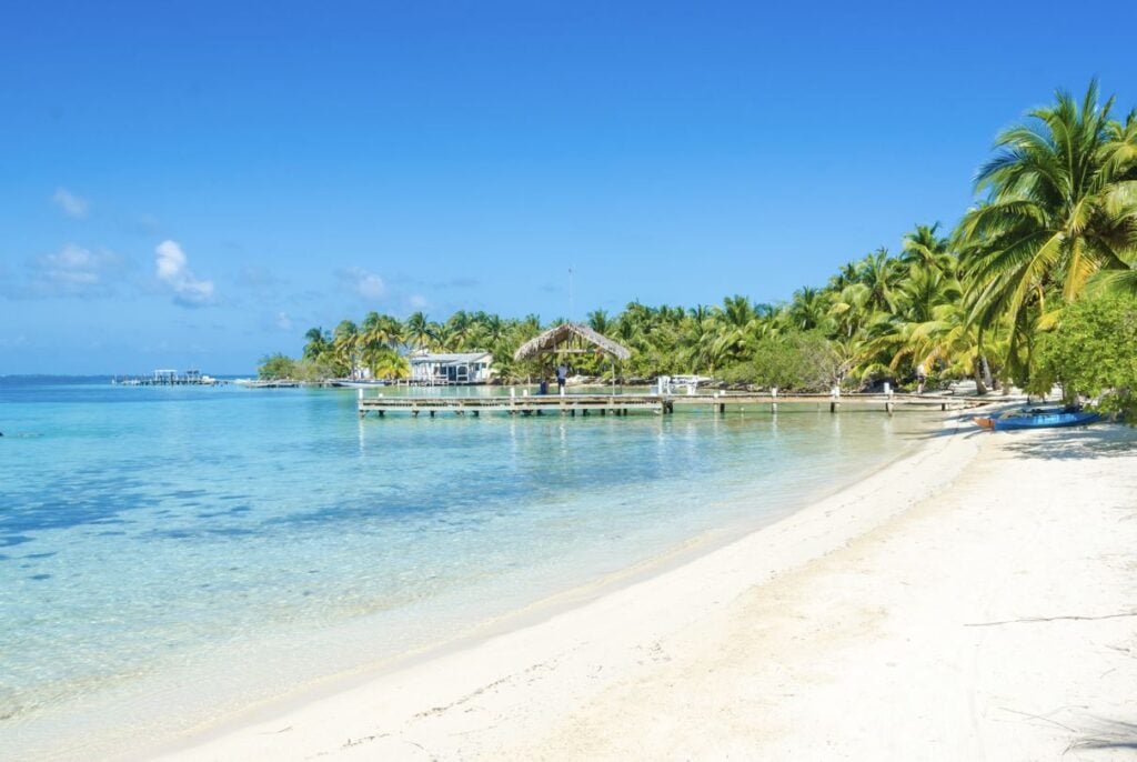 White sand beach in Belize with aqua blue clear water and palm trees